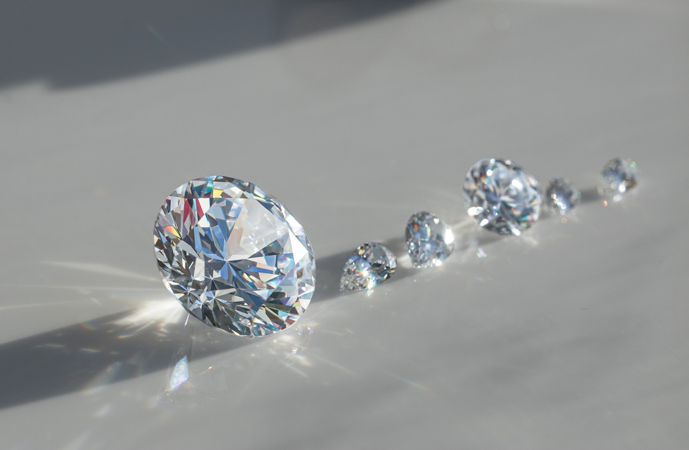 Several loose diamonds on a white table lined up by size.